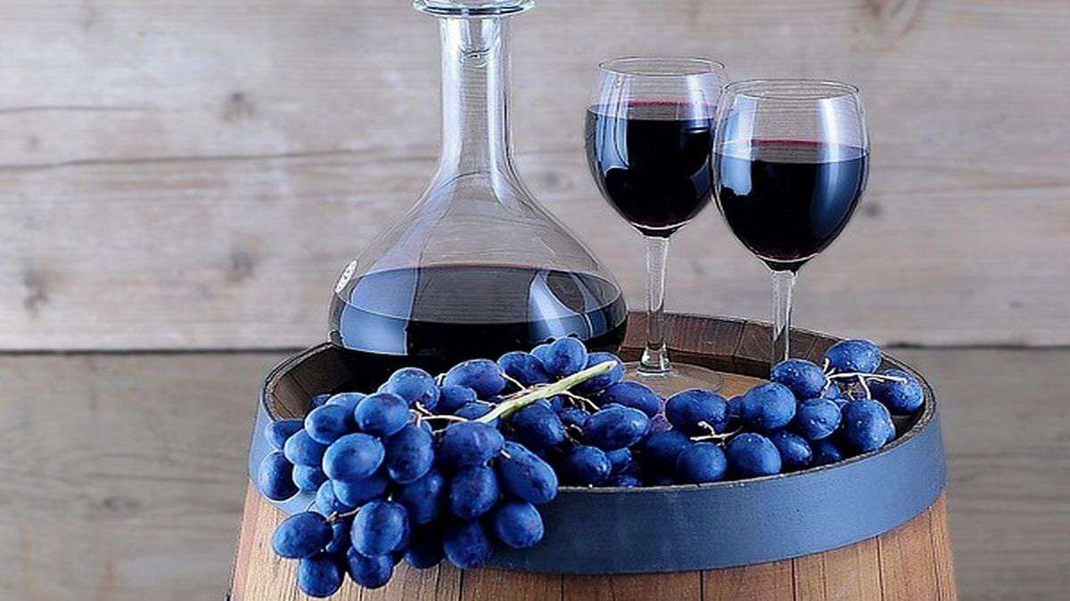 Garrafa de uvas e barril de vinho tinto