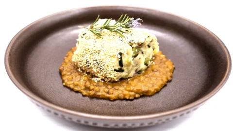 La ricetta del Cotechino di ceci e verdure di stagione in crosta di sesamo su letto di lenticchie, trionfo salutare di legumi firmato dallo chef Luca Vaghi